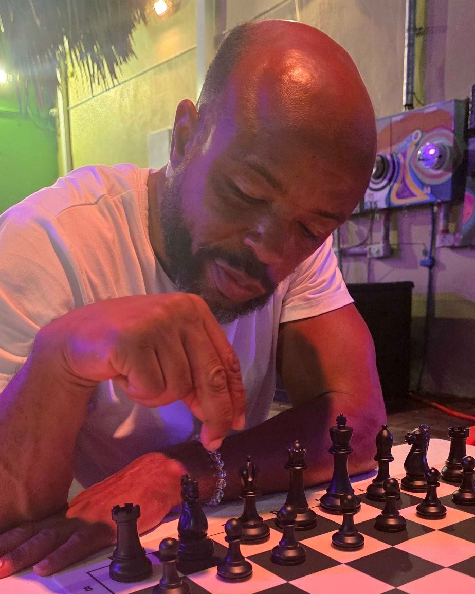 Mel, the club's newest member, deep in thought over the board under the tiki at Kava Social on a rainy free play night