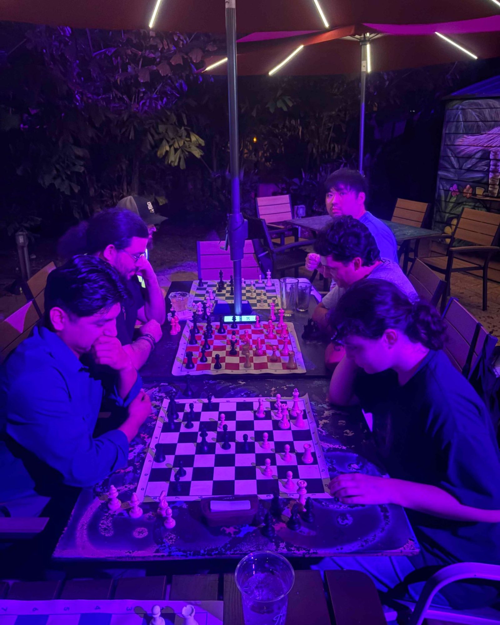 Players at three boards under the lit umbrellas at Adobe Kava on a Thursday study night