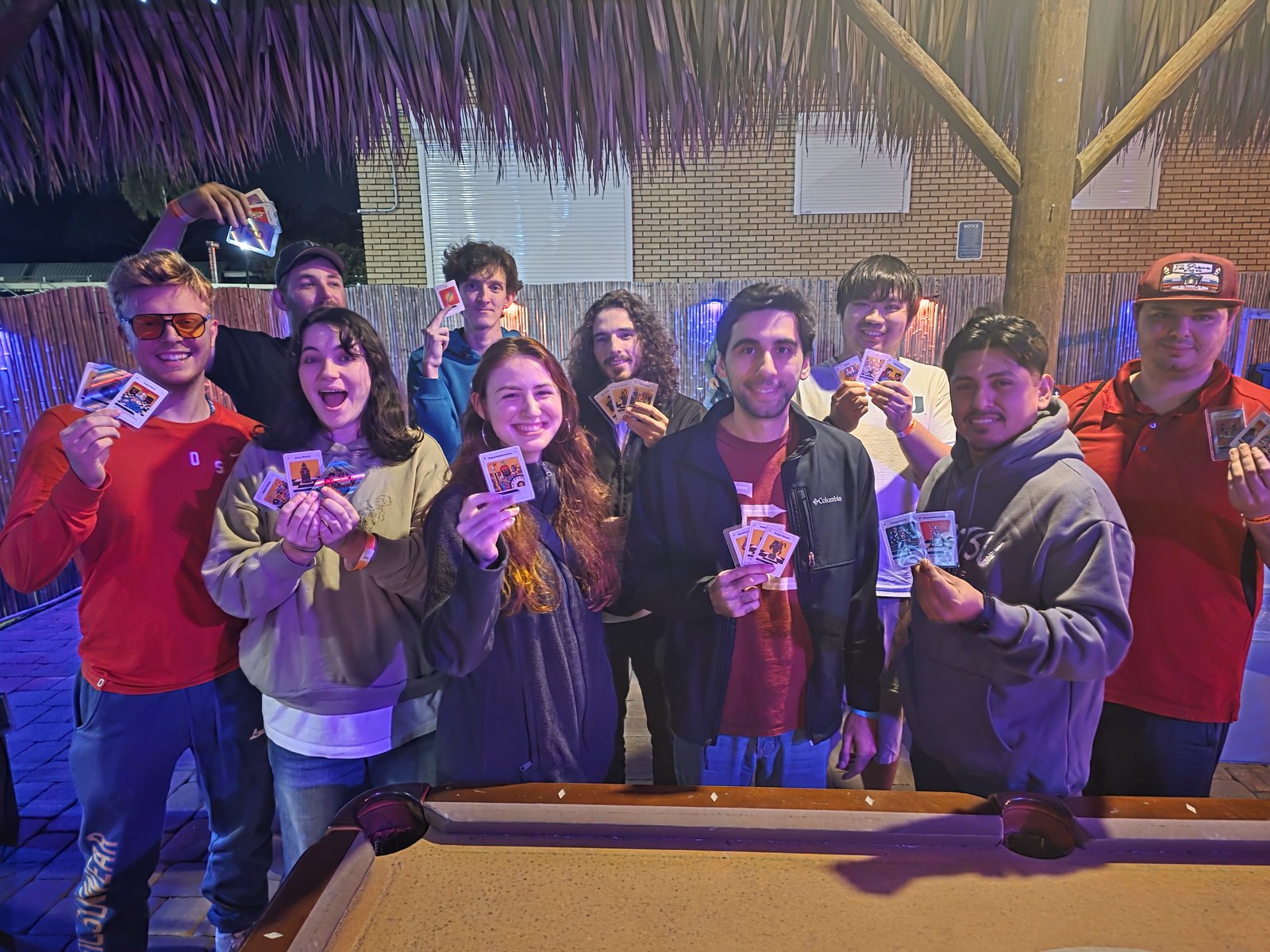 Eleven club members under the tiki holding up their new Chess Trading Cards