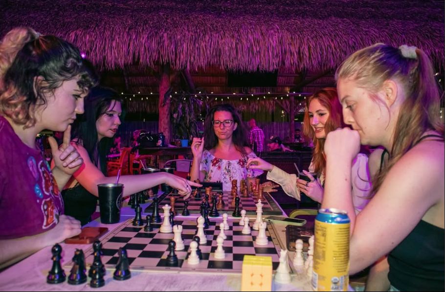 Three members laughing over a board on a club night
